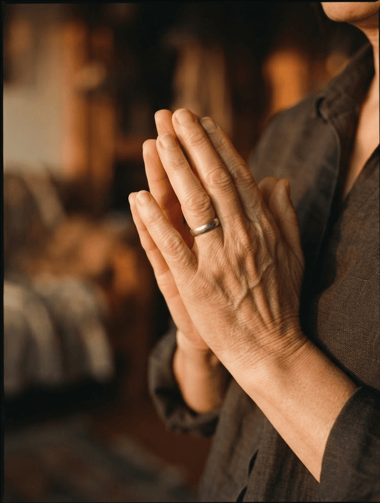 A close-up of hands pressed together in warm dusk light.